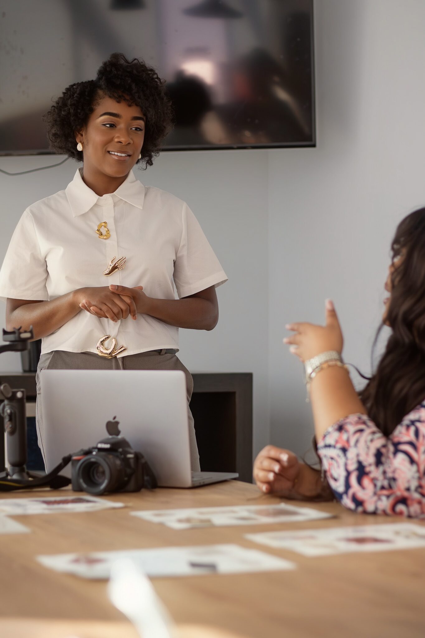 All Eyes On You Branding marketing agent having a consultation with a client looking at images in a luxury office. The client is speaking and the marketing assistant and pleasantly listening to feedback.